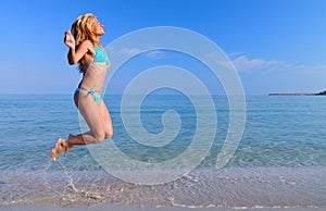 Young woman in sportswear running near still sea edge and smiling