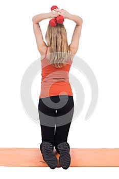 Young woman in sportswear training back with the red dumbbells.