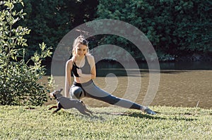 Young woman in sportswear trains in an outdoor Park and plays with dog