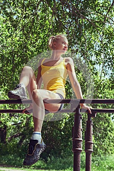 Young woman in sportswear working out outdoors in a park on sunny summer day.