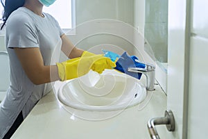 Young woman spraying disinfectant in the sink