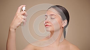 Young woman sprays a facial spray mist or thermal wate