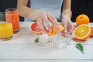 Young woman squeezes orange juice using a glass juicer