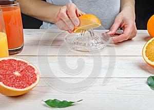 Young woman squeezes orange juice using a  glass juicer