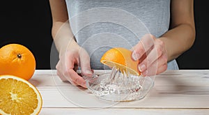 Young woman squeezes orange juice using a manual glass juicer