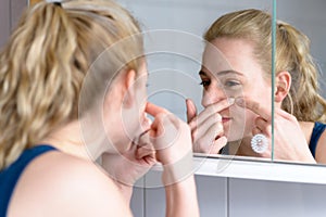 Young woman squeezing her pimples