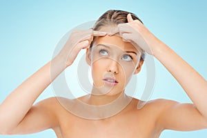 Young woman squeezing pimple on her face