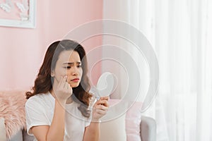 Young woman squeezing pimples in front of mirror