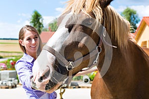 Young woman in the stable with horse and is happy