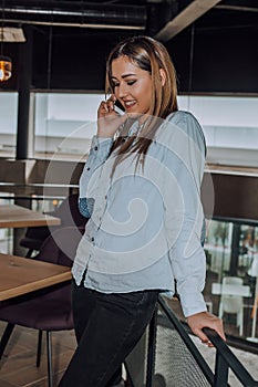 Young woman stading and talking on the phone in cafe