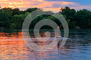 Young woman on stand up paddle board paddleboard, SUP paddleboarding along the Dnieper river at sunset