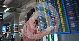 young woman standing in the airport looks carefully checking flight on information board. Female tourist looks first at