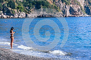 Young woman standing alone at beach and look at her phone. Concept good, bad signal