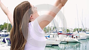 Young woman standing alone on pier. Inspired carefree female raising her arms up in slow motion