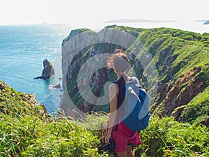 Young woman standing alone on a rocky cliff, Girl tourist photographer on the background of beautiful wildlife