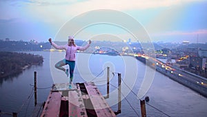 Young woman in standing asana on the edge of bridge, yoga practice, adrenaline