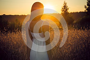 Young woman standing back at sunset in summer