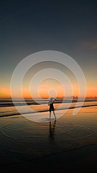 Young woman standing on the beach at a beautiful sunset