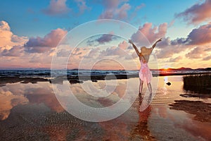 A young woman standing on the beach at the sunset