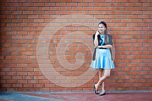 Young woman standing with brick wall