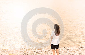 Young woman standing on cliff and looking forward on the background of the sea, sky. lady tourist on top of a mountain enjoying