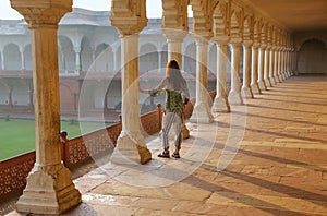 Young woman standing in colonnade walkway leading to Diwan-i- Khas in Agra Fort, Uttar Pradesh, India