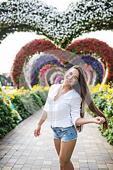 Young woman standing in colorful heart shaped flowers alley in Dubai Miracle Garden
