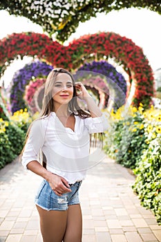 Young woman standing in colorful heart shaped flowers alley in Dubai Miracle Garden