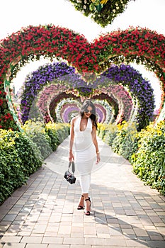 Young woman standing in colorful heart shaped flowers alley in Dubai Miracle Garden