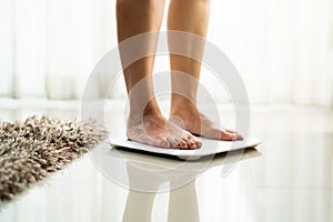 Young woman standing on digital weight scale