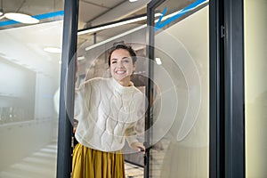 Young woman standing at the door, smiling happily