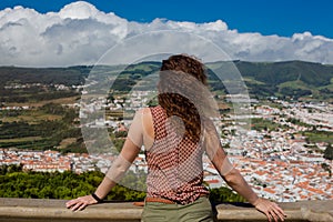 A young woman is standing in front of Angra do Heroismo, Terceira, Azores, Portugal.