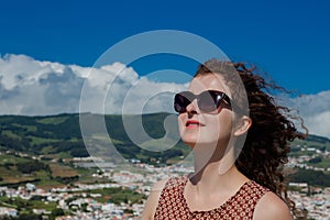 A young woman is standing in front of Angra do Heroismo, Terceira, Azores, Portugal.