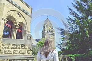 Young woman is standing in front of the old building with a old church nearby