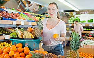 Young woman standing with full grocery cart during shopping