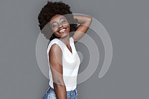 Young woman standing on gray touching hair smiling happy