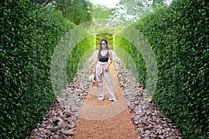 Young woman standing in green bushes labyrinth , hedge maze