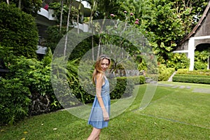 Young woman standing on green grass near resort house.