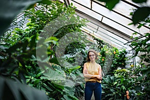 Young woman standing in greenhouse in botanical garden. Copy space.