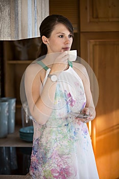 Young woman standing in kitchen and drinking coffe