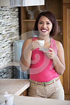 Young woman standing in kitchen drinking coffee