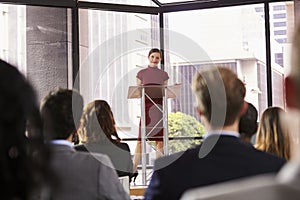 Young woman standing at lectern presenting business seminar