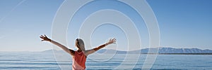 Young woman standing by the morning sea greeting the new day