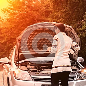 Young woman standing near the broken car. The girl opened the hood and look at the engine. Refit woman car