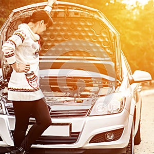 Young woman standing near the broken car. The girl opened the hood and look at the engine. Refit woman car