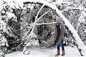 Young woman standing near fallen tree after sleet load and snow in a snow-covered winter park. Snowy winter, frosty day photo