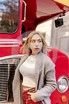 Young woman standing near London red bus