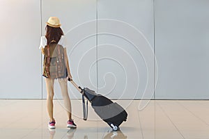 Young woman is standing near window at the airport and watching