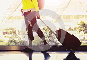 Young woman is standing near window at the airport and watching plane before departure