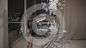 Young woman standing near window with a spectacular view of a night city.